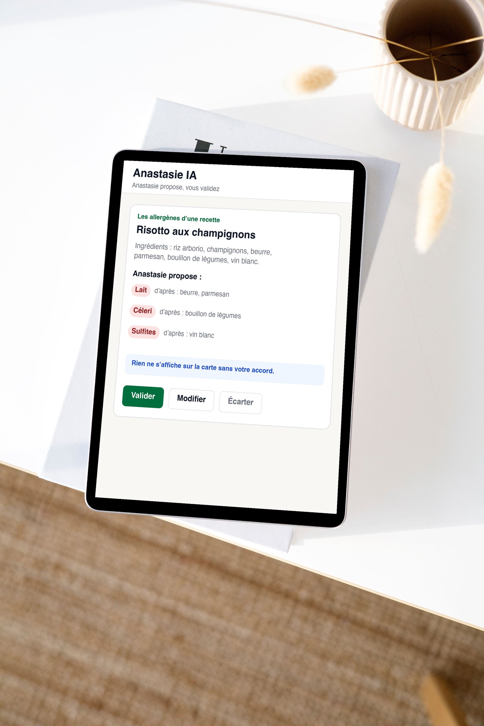 Une tablette montre Anastasie IA qui propose les allergènes d’une recette, à valider (données fictives)